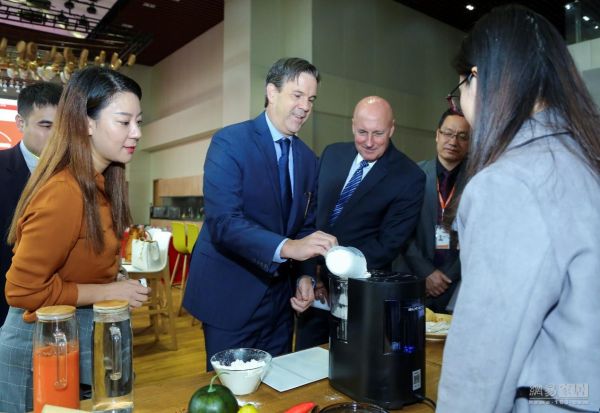 活动现场,美国伊士曼化工公司特种塑料事业部副总裁兼总经理Burt Capel(左二)正在体验九阳智能面条机L20“面霸”